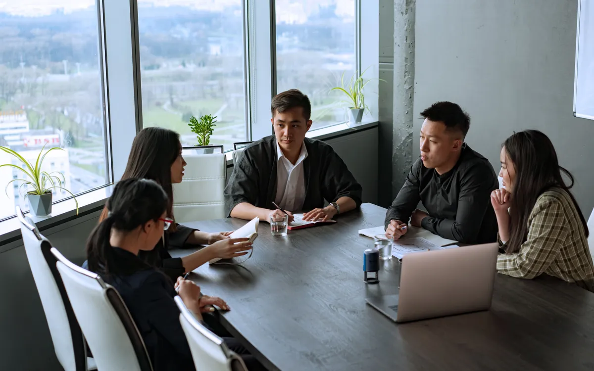 People reviewing documents together around a table in a meeting.